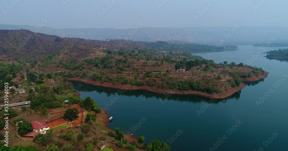 Aerial shot of river running along fields with reddish soil, houses around Aerial shot of river running along fields with reddish soil, houses around