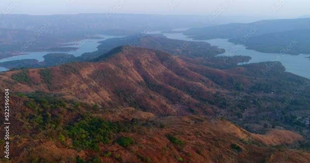Aerial shot of river running between hills with tropical forest at sunset Aerial shot of river running between hills with tropical forest at sunset
