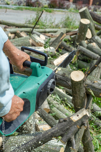 A male uses a chainsaw to cut up a log into firewood.