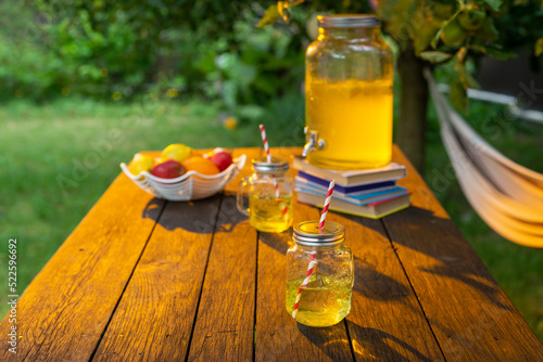 drink station with small bottles and homemade lemonade on wooden terrace with abstract night light bokeh of night festival in garden, copy space for display of product or object presentation.