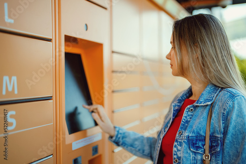 Obraz na plátně Woman picks up mail from automated self-service post terminal machine