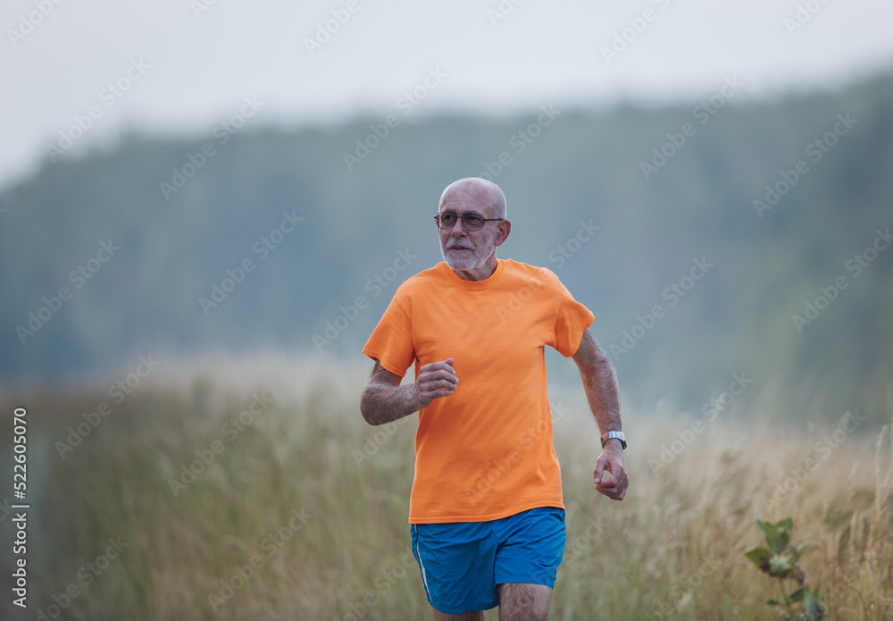 Fototapeta premium Senior man running in forest in summer time