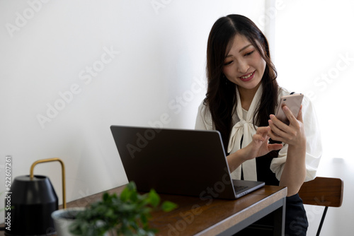 A Japanese woman checking smartphone by remote work in the small office