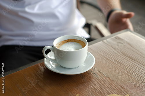 White cup of coffee with milk on a wooden table