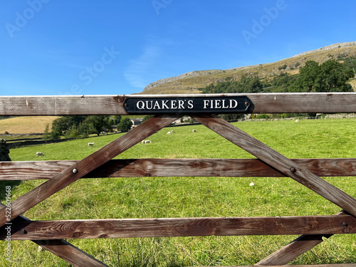 Quaker's Field notice, on a farm gate with sheep, fields, and hills in the distance near, Austwick, Settle, UK photo