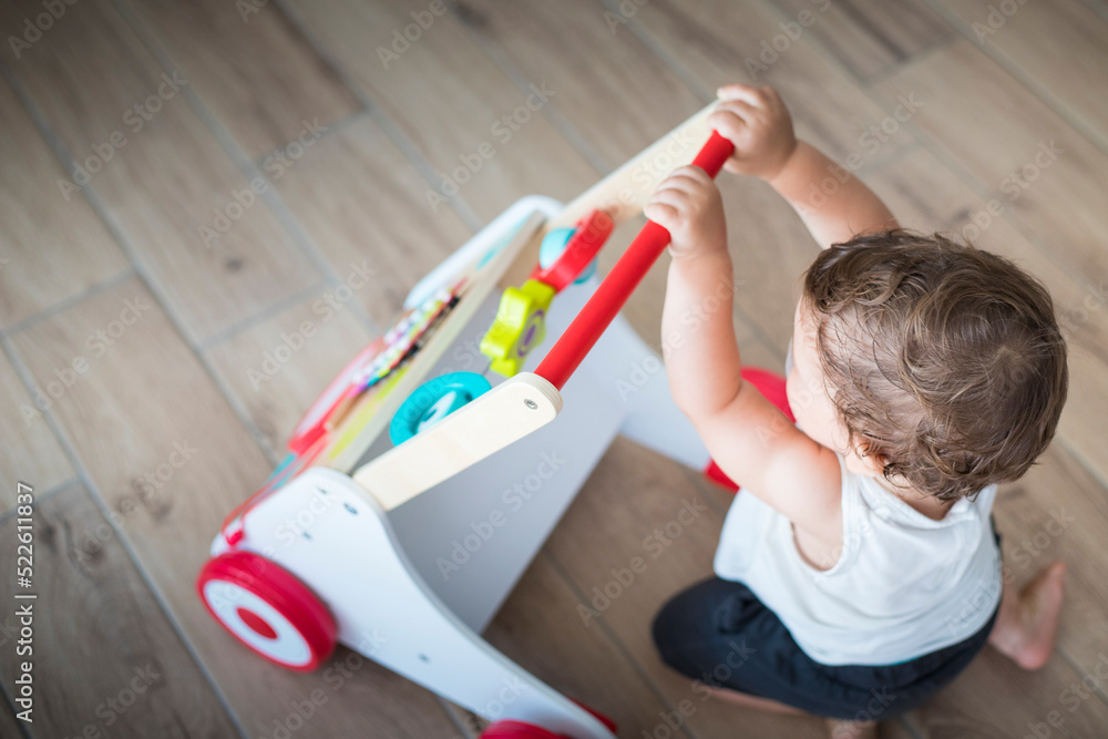 Baby boy, caucasian, one year old, playing and learning with walking toy. Top view, indoor. Baby boy, caucasian, one year old, playing and learning with walking toy. Top view, indoor.