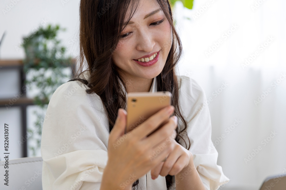 A Japanese woman checking smartphone by remote work in the small office A Japanese woman checking smartphone by remote work in the small office