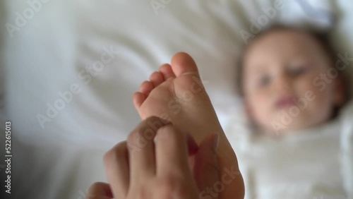 Mom massages baby on the bed
