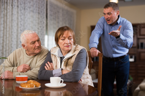 Adult son argues with his elderly parents at home. High quality photo © JackF