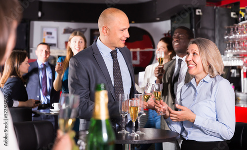 Happy man and woman drinking alcohol and having conversation on corporate party