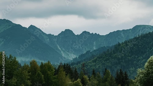 Time-lapse mountain range covered with rolling rainy clouds. Mountain peaks in Tatra mountains, Poland. Cloudy summer day. Epic rocky highlands and hills covered with green pine trees forest