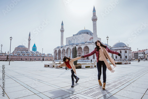 mother playing around with her daughter in the square while visiting mosque in konya turkiye photo