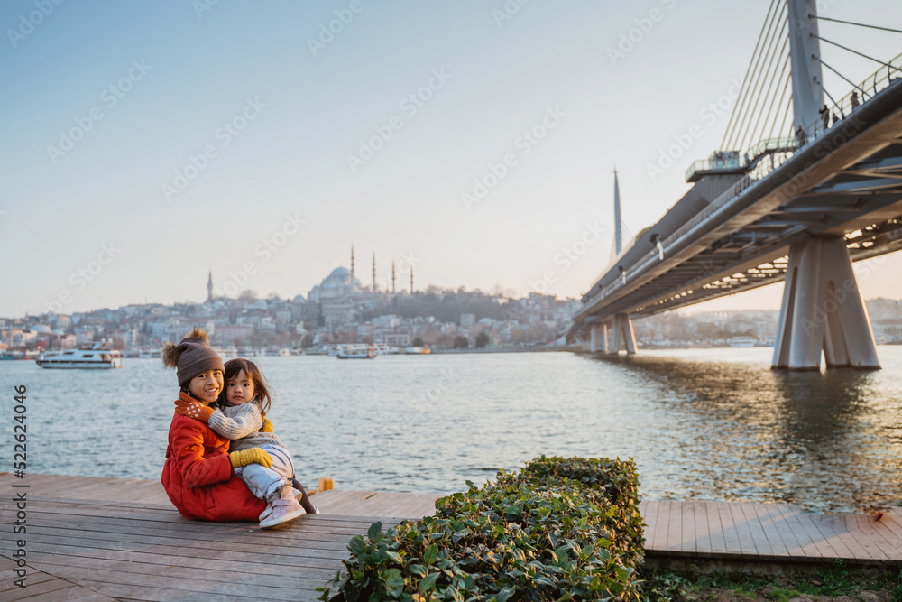 happy sister sitting down with the view of bosphorus sea and city of istanbul turkey
