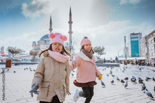 happy kids playing with pigeons in taksim square turkey during winter photo