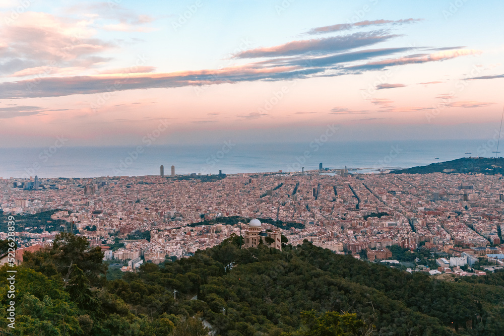 Barcelona cityscape of the Eixample with the Observatori Fabra in the middle looking at the sea from Tibidabo Mountain at Sunset golden hour sky