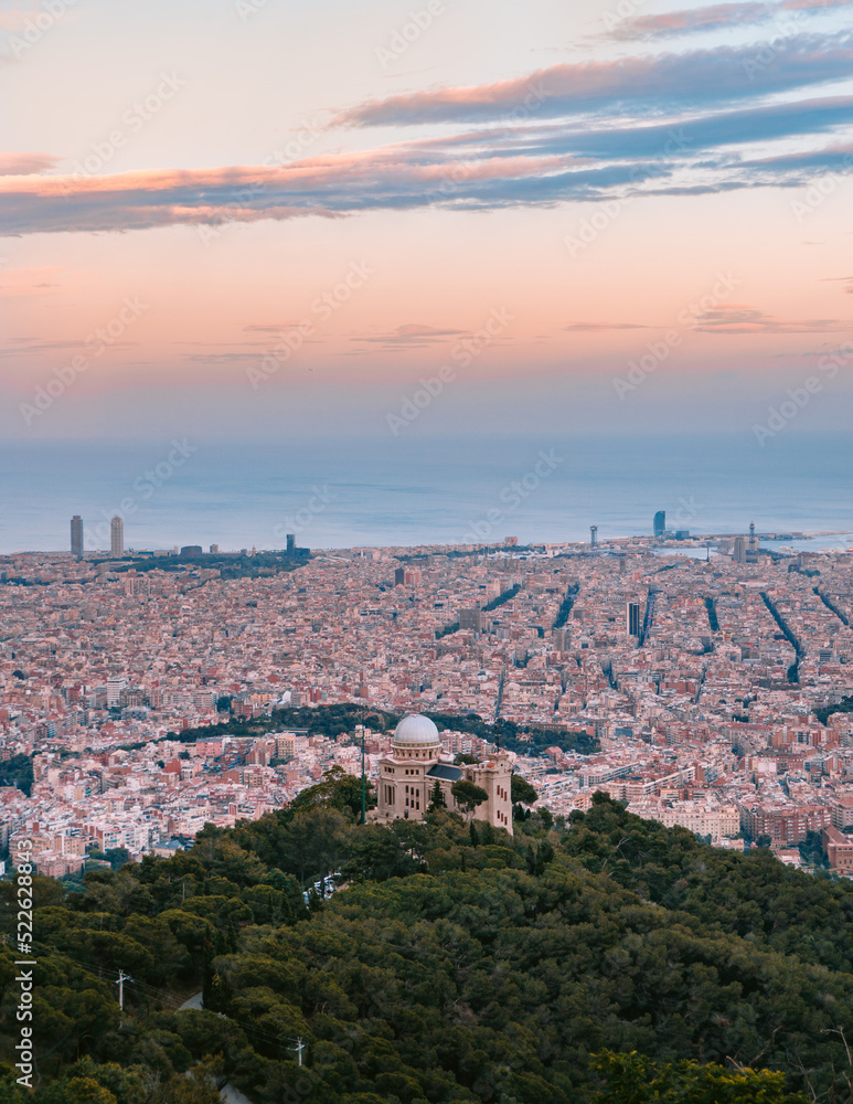 Barcelona cityscape of the Eixample with the Observatori Fabra in the middle looking at the sea from Tibidabo Mountain at Sunset golden hour sky