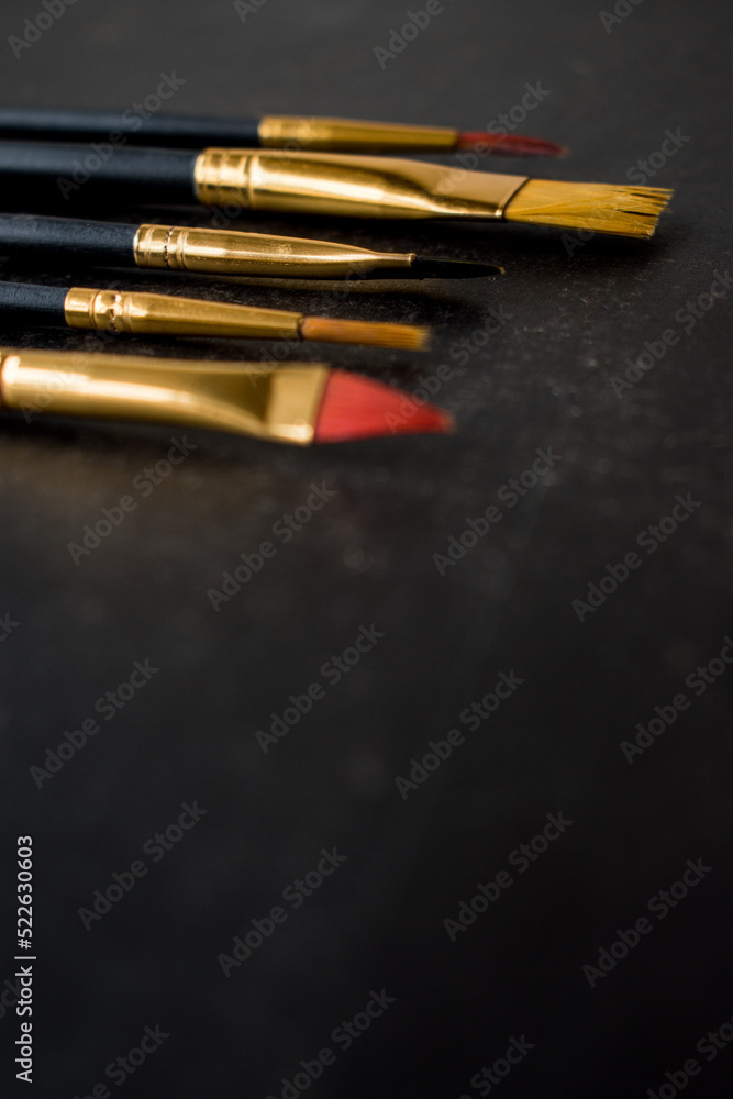 Different golden make-up brushes on black background Different golden make-up brushes on black background