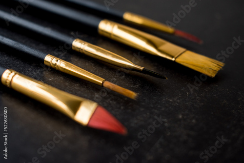 Different golden make-up brushes on black background