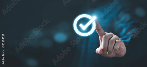 Businessman hand touching glowing correct sign mark with copy space area for document approval and project approve concept. photo