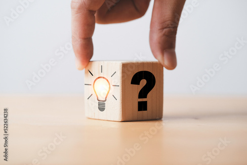 Hand flipping between question mark and glowing lightbulb for question and answer of problem solution concept.