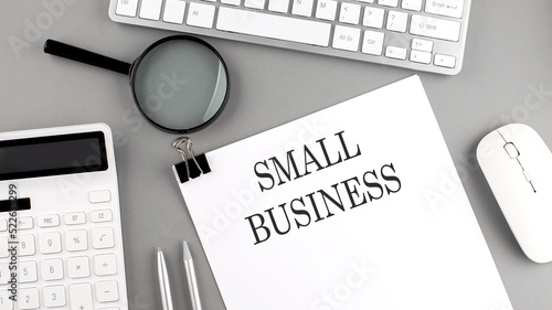 SMALL BUSINESS written on paper with office tools and keyboard on the grey background