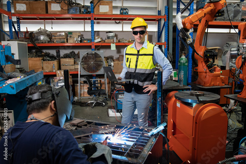 Obraz na plátne Engineer wearing helmet and hi visible vest working in factory hold laptop compu