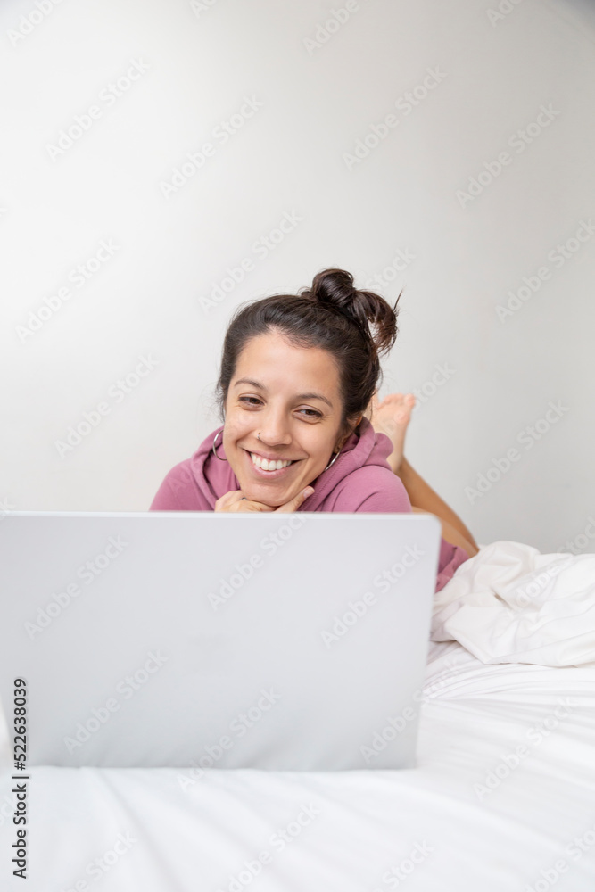 Caucasian woman using laptop computer on white-sheeted bed Caucasian woman using laptop computer on white-sheeted bed