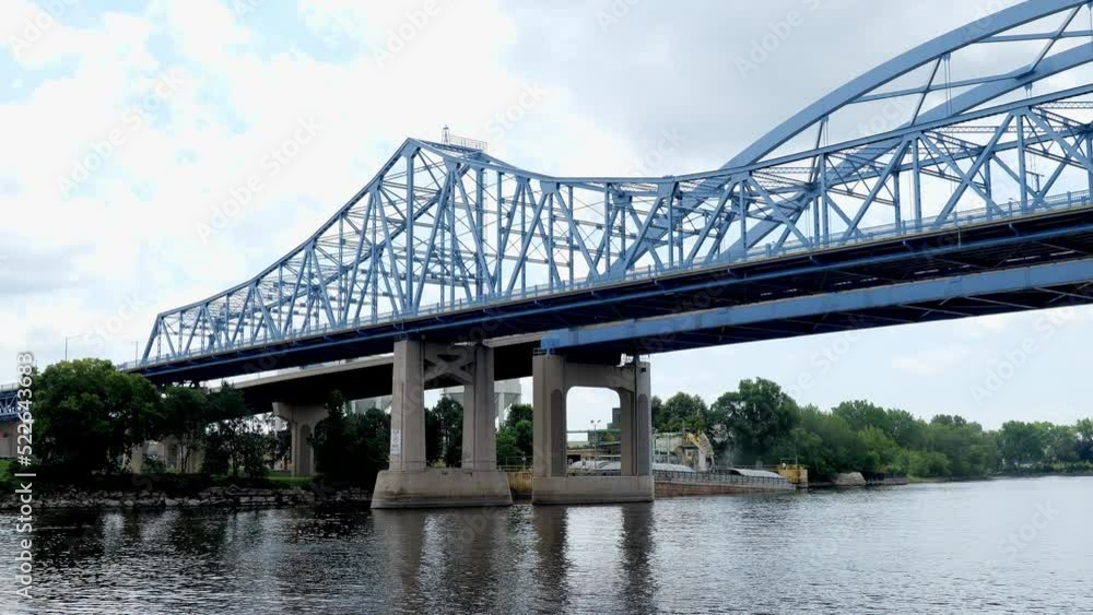 Two bridges over the Mississippi River at La Crosse, Wisconsin are viewed from a boat P.O.V. on the water as it approaches. Parallel and adjacent bridges with tied-arch and cantilever truss designs. Two bridges over the Mississippi River at La Crosse, Wisconsin are viewed from a boat P.O.V. on the water as it approaches. Parallel and adjacent bridges with tied-arch and cantilever truss designs.