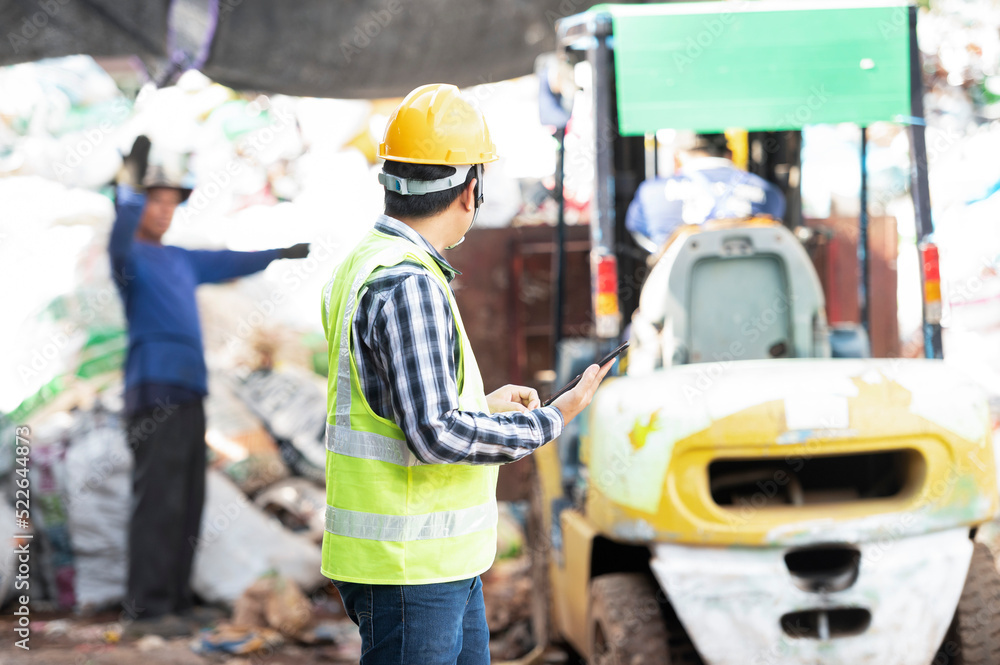 Close-up of a worker with a recycling bin moving a forklift in a steel mill waste collection plant. Close-up of a worker with a recycling bin moving a forklift in a steel mill waste collection plant.