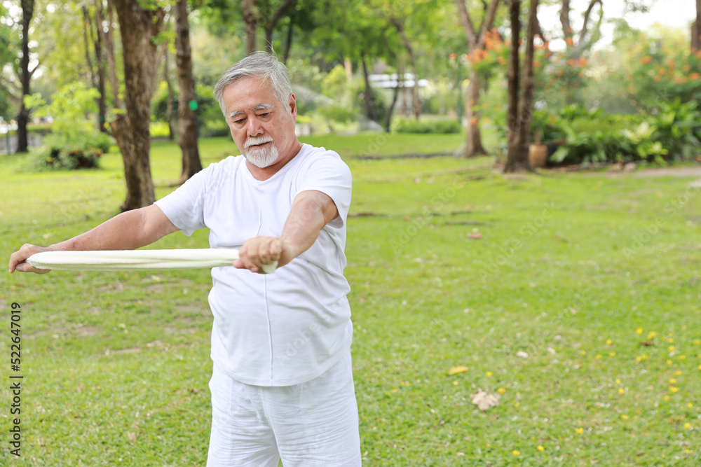 Asian senior man practice yoga excercise, tai chi tranining, stretching and meditation together with towel for relax healthy in park outdoor after retirement. Happy elderly outdoor lifestyle concept Asian senior man practice yoga excercise, tai chi tranining, stretching and meditation together with towel for relax healthy in park outdoor after retirement. Happy elderly outdoor lifestyle concept