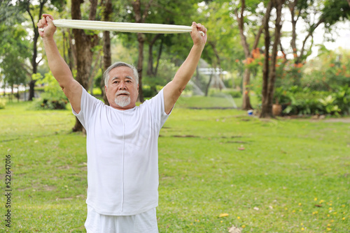 Asian senior man practice yoga excercise, tai chi tranining, stretching and meditation together with towel for relax healthy in park outdoor after retirement. Happy elderly outdoor lifestyle concept