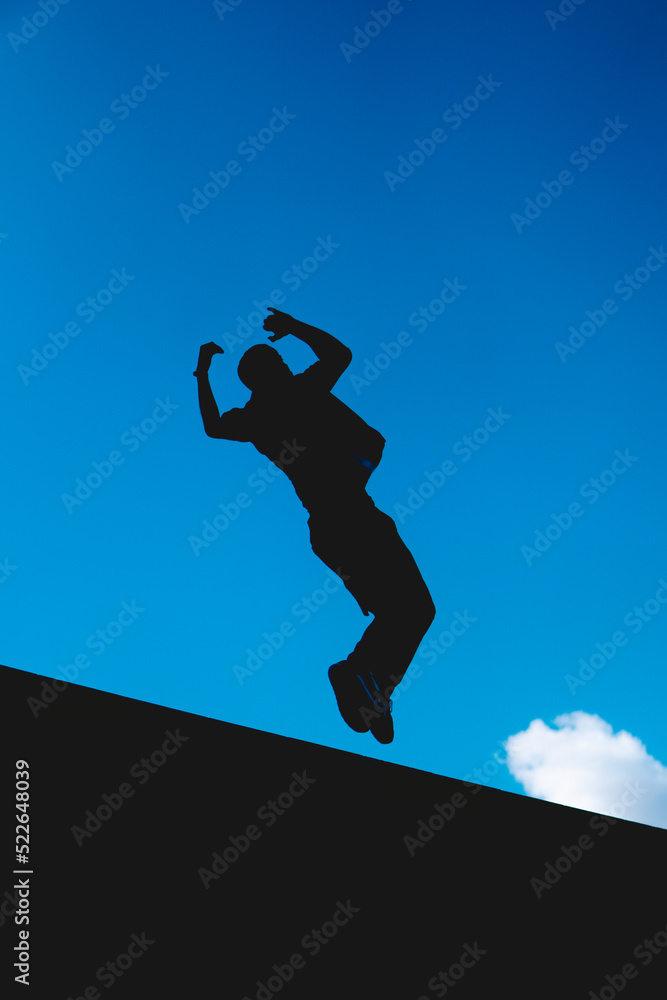 Black silhouette in the air of a man doing an extreme somersault with the sky in the background. Black silhouette in the air of a man doing an extreme somersault with the sky in the background.