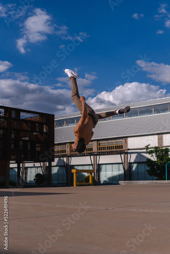 A young Latino boy with dark skin practicing an extreme breakdance move. Hispanic man practicing stunts. © Wacha Studio