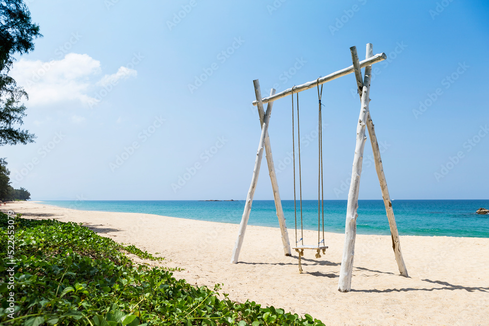 Relaxing by the sea, wooden swing on white sandy beach on tropical island in south of Thailand, summer outdoor day light