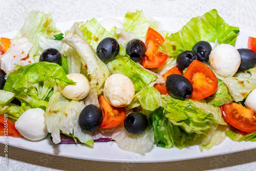 Isolated plate with salad on a white background. Salad of quail eggs, greens, tomatoes and olives