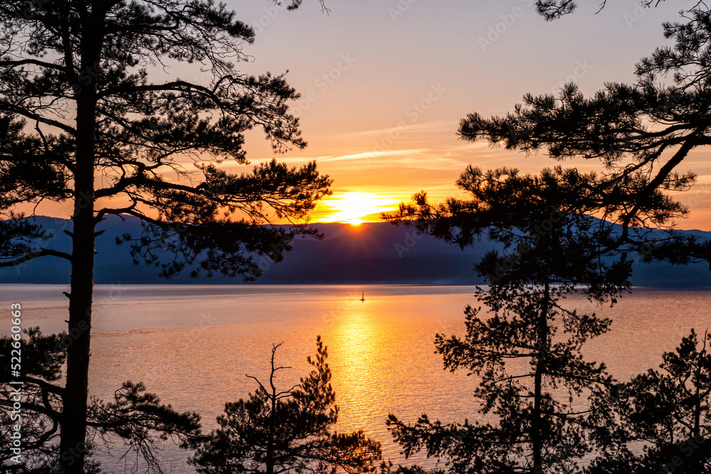 View of the picturesque lake through the trees at sunset