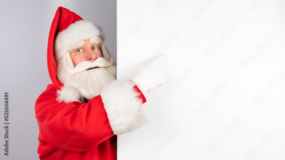 Santa Claus peeks out from behind an ad on a white background. Merry Christmas. Santa Claus peeks out from behind an ad on a white background. Merry Christmas.
