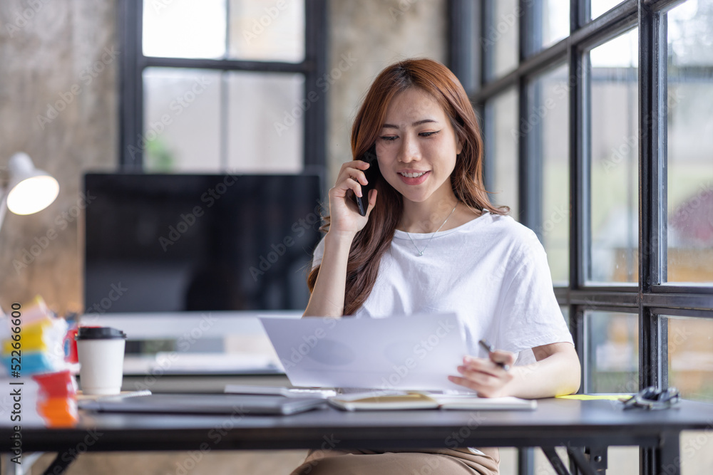 Business Asian woman freelancer talking phone and work on computer laptop from home office Doing accounting analysis report real estate investment data, Financial and tax systems concept.
