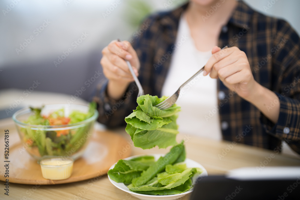 Happy beautiful Asian woman eating healthy food with vegan.salad in the kitchen at home. Happy beautiful Asian woman eating healthy food with vegan.salad in the kitchen at home.