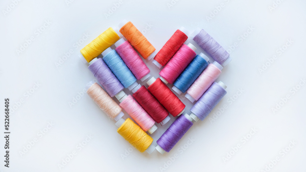 Multicolored spools of thread in shape of heart Multicolored spools of thread in shape of heart