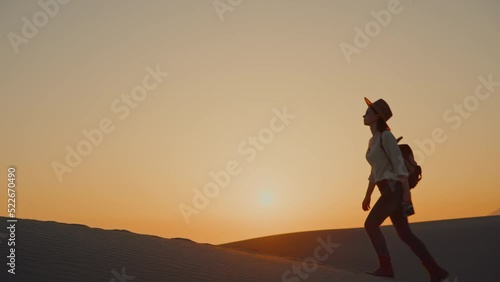 Attractive woman aith a retro camera walking on a sand dune in the sun photo