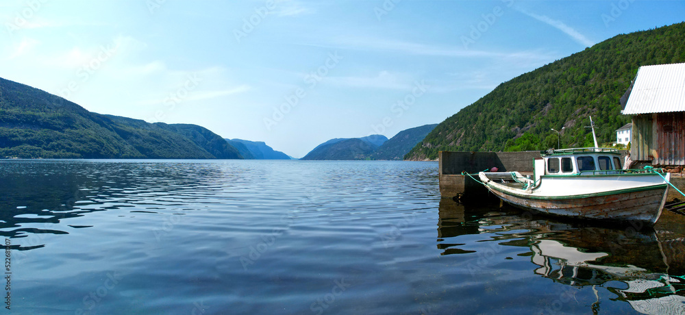 Boat tied to the shore by a house in a fjord, Northern Europe extra wide panorama