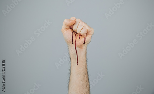 Conceptual bleeding clenched fist over gray background