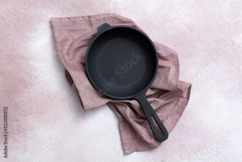 Cast iron skillet on a light background. Frying pan and kitchen towel. Kitchen utensils. Empty place. Top view.