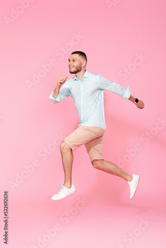man in summer clothes jumping on pink background.