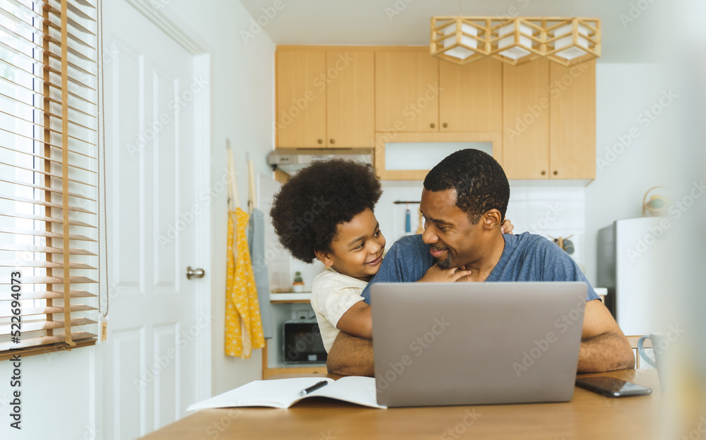 Portrait of Black African American father with his little son in the kitchen, Happy Single Dad playing with his boy while working at home on Laptop, Freelance, fatherhood concept Portrait of Black African American father with his little son in the kitchen, Happy Single Dad playing with his boy while working at home on Laptop, Freelance, fatherhood concept