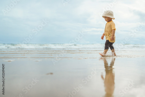 Asian boy walking on the beach. Adorable child in outdoor summer holiday vacation
