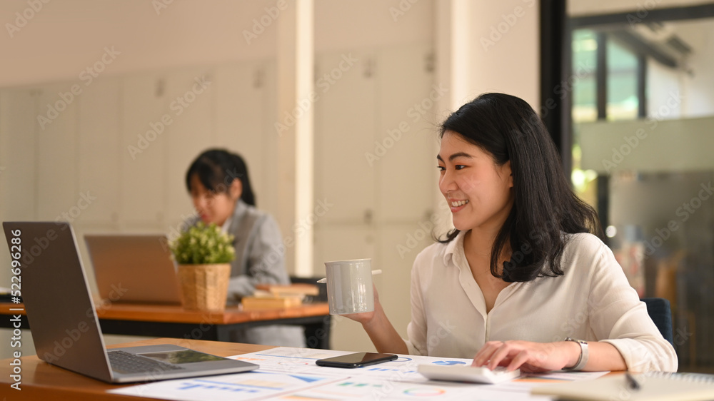 Asian businesswoman using laptop, preparing report analyzing work results at her workplace Asian businesswoman using laptop, preparing report analyzing work results at her workplace
