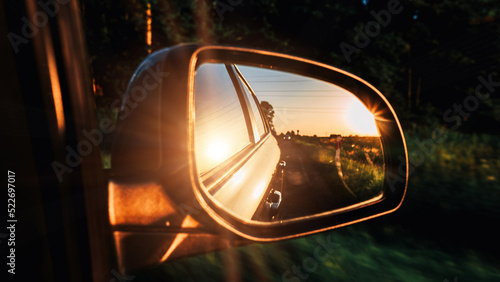Car sunset road mirror. Summer sun, highway car road reflection in mirror. Vacation trip concept. © Maksym