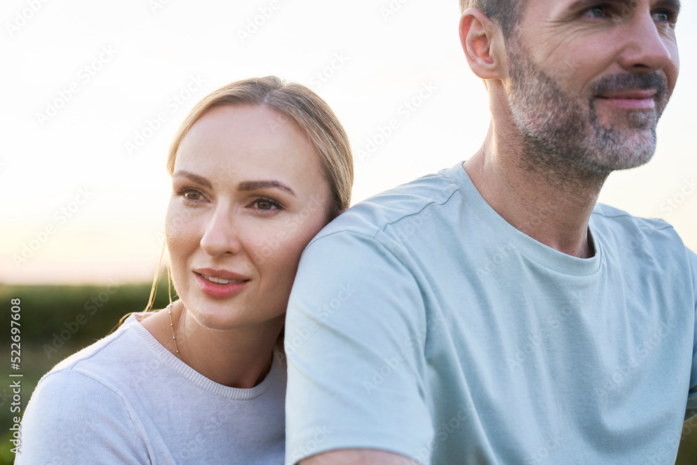 Caucasian middle aged couple standing behind each other outdoors in the summer Caucasian middle aged couple standing behind each other outdoors in the summer